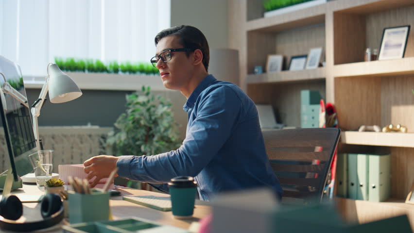 Inspired man checking notebook flipping pages at modern office. Closeup eyeglasses freelancer preparing project having fresh idea at room. Brunette businessman looking at computer screen working alone | Shutterstock HD Video #1104814487