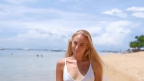 portrait of beautiful blonde woman spending time on white sand beach at summer time