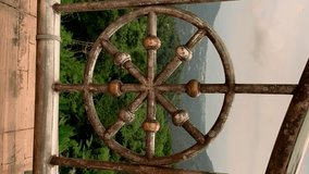 A green landscape of trees through a golden round iron fence in a Buddha temple in Thailand. Slow motion filmed video vertically. High quality footage