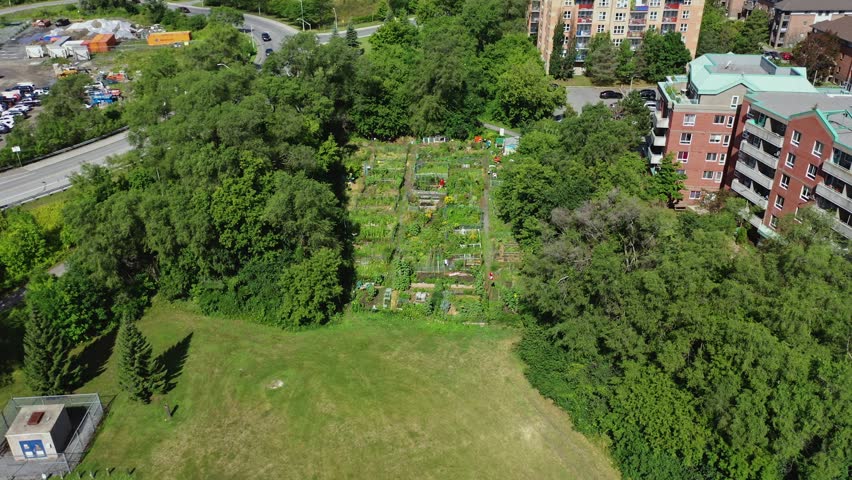 Drone shot of a community garden beside apartment buildings with Canadian flag waving in Ottawa Ontario