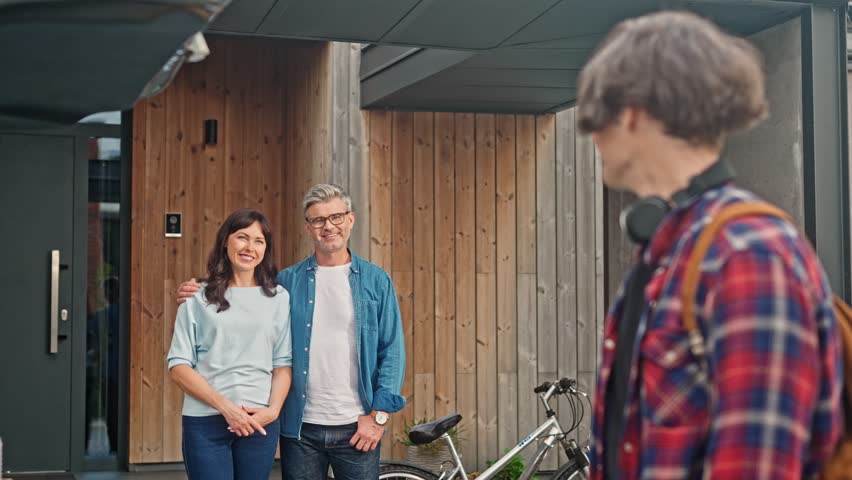 Teenage boy moves to another house and says goodbye to his parents. Young guy entering university and putting his belongings into car. Parents are happy with their son's success.
