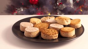 Spanish Christmas cookies, polvorones mantecados, served on a plate against the backdrop of a festive Christmas tree adorned with garlands