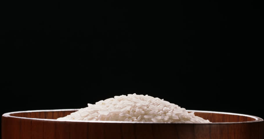 Rice being poured raw wooden cup side view black background Asian Chinese Thai Japanese Indian ethnicities. Slow and calm oriental lifestyle and culture Royalty-Free Stock Footage #1104843203