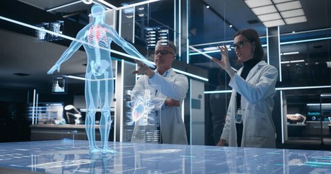 Two Bioengineers Working With Computer-Powered Animated VFX Hologram Of Human Body And Organs In Futuristic Lab. Man And Woman Researching Blood Flow, Developing Innovative Healthcare Solutions. Video Stok