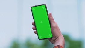 Point of View of male man outdoors Using Phone With Green Mock-up Screen Chroma Key Surfing Internet Watching Content Videos Blogs Tapping on Center Screen