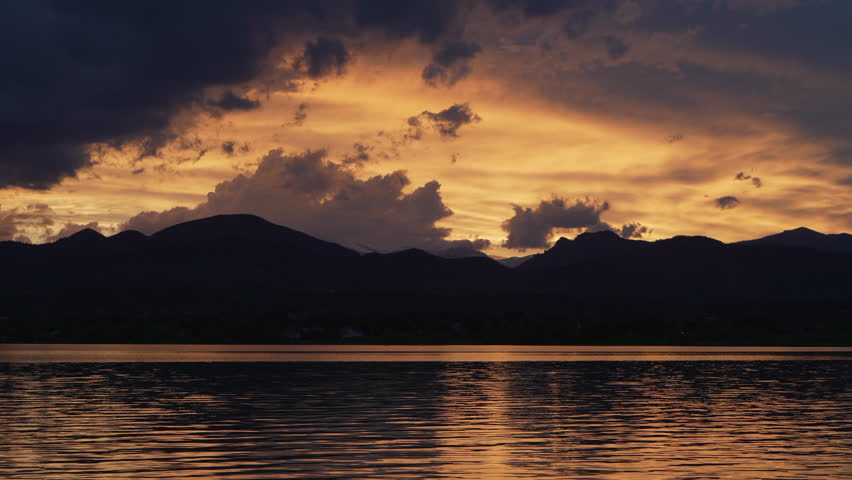 dramatic sunset sky and clouds over Rocky Mountains and lake in northern Colorado