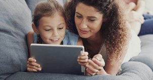 Tablet, mother and child streaming video online, internet and website in a home couch or sofa and bonding together. App, happy and parent search the web with kid on social media in a house lounge
