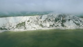 Distant view Beachy Head Lighthouse, white cliffs, foggy sky and sea taken by dji mini 3 pro drone in Eastbourne England. 4K video