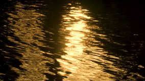 Abstract nature background 4K slow motion video clip of golden light reflecting on sea, lake or river water with liquid gold ripples and reflections