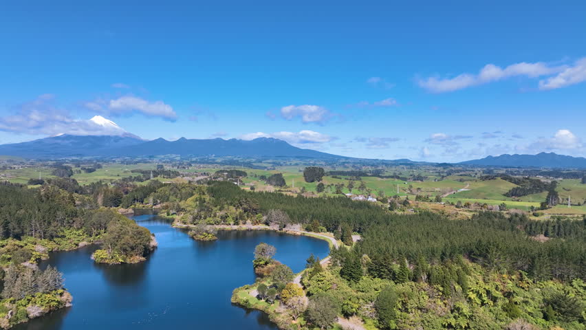 Flight across scenic lake and quintessential Taranaki New Zealand farmland
