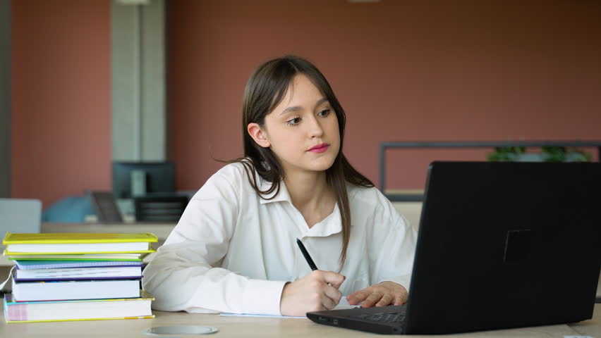 Focused girl using laptop in class, attractive female student learning language, watching online webinar, listening audio course, e-learning education concept
