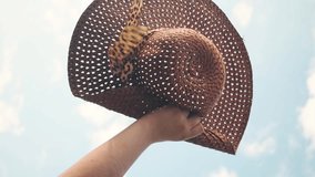 Vertical video of hand holding a wicker hat with animal print ribbon - Powered by Shutterstock - Get 15% off with code: PIKWIZARD15