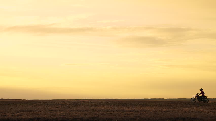 Silhouette of motorcycle riding on dusty road. Motorcyclist drives his motorcycle at high speed. Motorcyclist participating in rally. High speed motorcycle race at sunset. Sports lifestyle concept | Shutterstock HD Video #1104855729