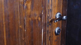 Close up shot of male hand opening old wooden locked door with iron antique handle in ancient building. histotic, architecture. 4 k video