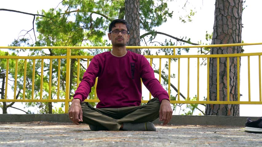 Man practicing yoga and meditation in mountains during luxury weather evening.