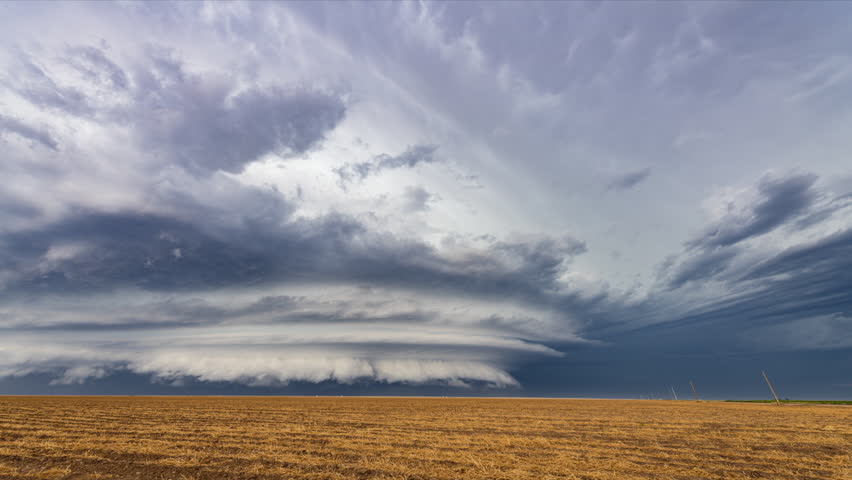 A mesocyclone weather supercell, which is a pre-tornado stage, passes over the Great Plains while pouring rain and cracking lightning highlight the horizon.
