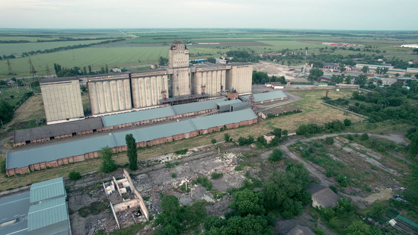 Aerial view of old abandoned grain processing and storing facility. Silos of old grain elevator with rail yard and storage buildings Royalty-Free Stock Footage #1104880713