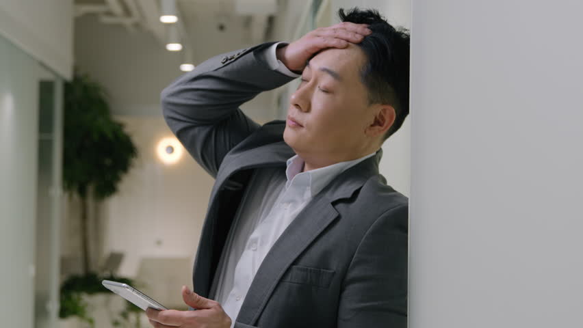 Asian tired ethnic man in office company hold mobile phone chinese korean japanese senior male businessman employer upset broken smartphone suffer headache worried loss debt failure cellphone problem Royalty-Free Stock Footage #1104882821