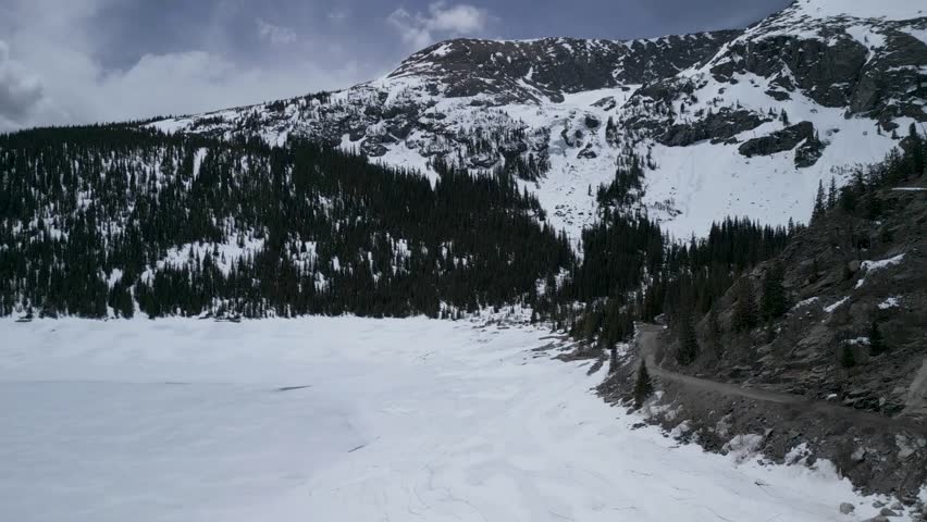 Flying across frozen lake towards snow covered mountains 