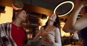 Dance Extravaganza: Three Joyful Girls Grooving at a Sunlit Cafe-Bar Bachelorette Party