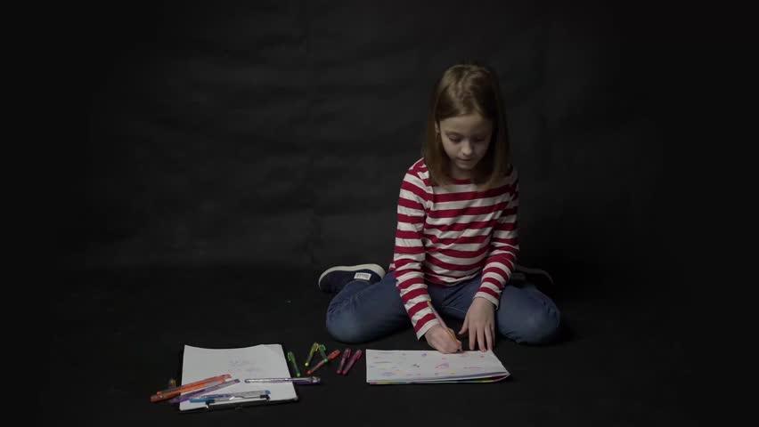 4k Little girl painting while sitting on floor at black background