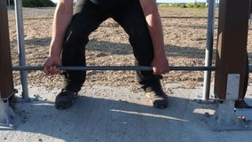 Deadlift at a outside gym. Man lifting barbell. Faceless video.