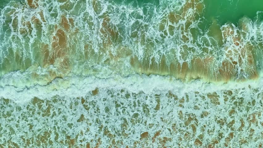 aerial top view the serene beauty of the scenery is breathtaking. 
The surface of the waves crashing on the sand breaks into beautiful patterns.
4K UHD 50 frame per second. Video slow motion Clip
 Royalty-Free Stock Footage #1104886213