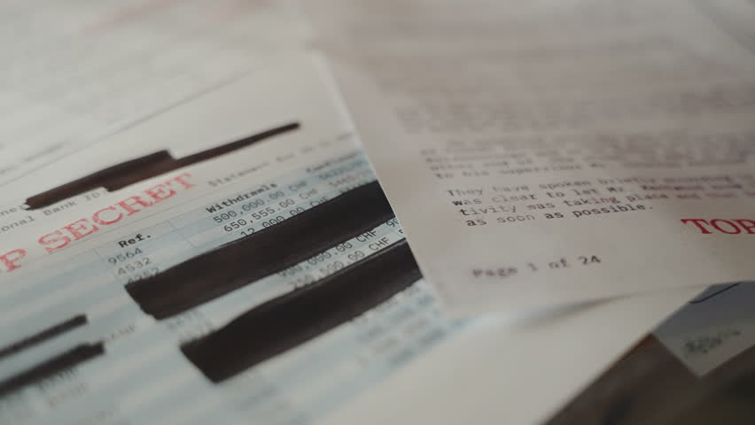Pan across top secret confidential bank files with red ink stamps on them. Account balance and activity statement with redacted black lines hiding information. Leaked or exposed documents on desk Royalty-Free Stock Footage #1104891457