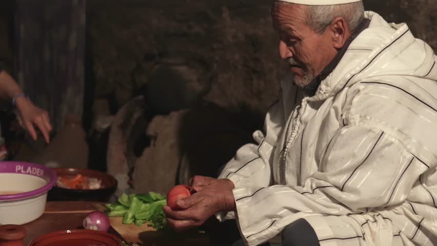 Berber family sitting in the old kitchen preparing traditional Moroccan food in tajin. Vintage Berber kitchen with black paint made with wood smoke, North African ethnic group. | Shutterstock HD Video #1104894219