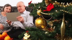 Seniors couple using tablet computer talking with video chat on Christmas.
