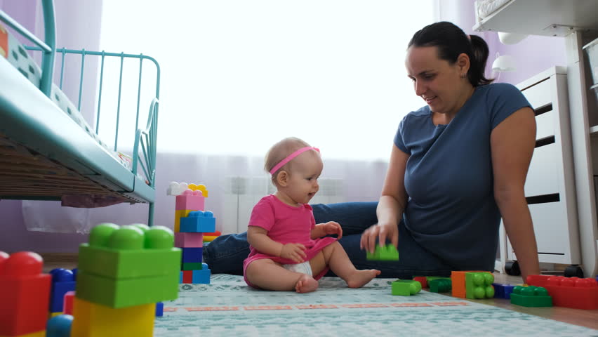 Happy young mother with baby daughter playing together in nursery, slow motion Royalty-Free Stock Footage #1104907771