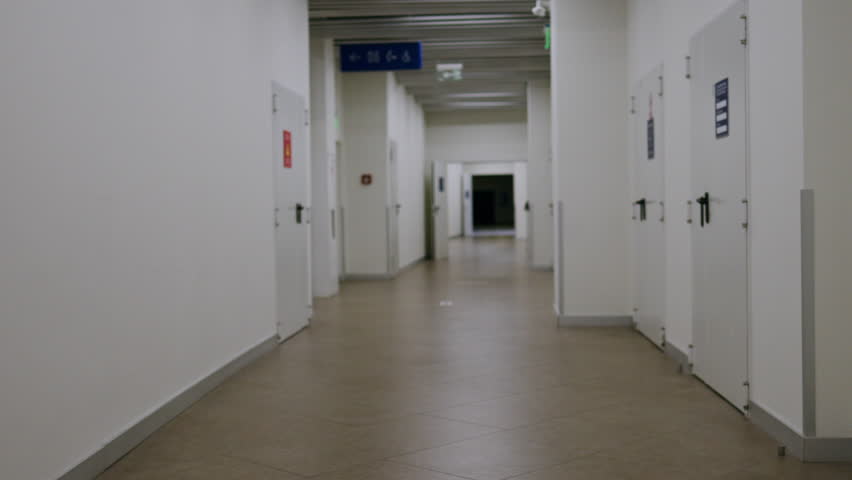 Smooth camera movement. industrial interior long corridor, deep passage, emergency exit, camera in motion endless corridor exit from parking to shopping mall. long corridor of office business center
