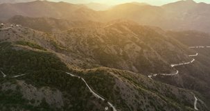 Aerial view of a serpentine mountain road at sunset. A beautiful landscape of nature with mountain ridges and peaks between which cars pass on the road. High quality 4k footage