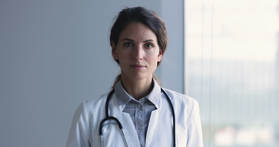 Head shot of happy successful Latina woman general practitioner or nurse, wear white uniform with stethoscope on shoulder look at camera, smile pose in hospital office. Professional GP doctor portrait Royalty-Free Stock Footage #1104912031