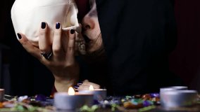 Witch hands holding and kissing a scary skull for a black magic ritual on a magical altar. Sorcerer rite of witchcraft and occultism. Halloween occult, esoteric and divination concept. - Powered by Shutterstock - Get 15% off with code: PIKWIZARD15