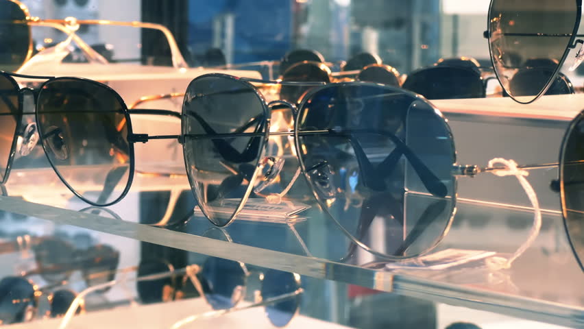 Sunglasses with gradient shading on the glass shelf of an optics store. Close-up