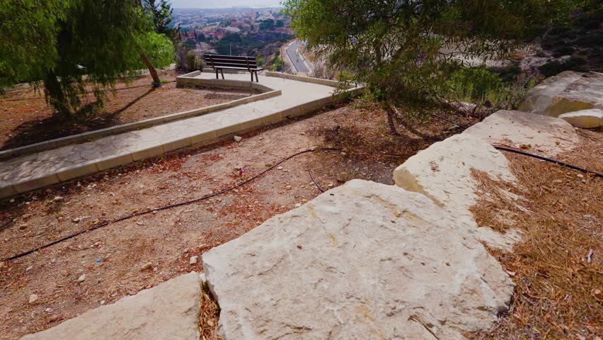 Time-lapse video in 4K. A solitary bench stands on a cliff of a mountain near a fence. The scene is located in a park.