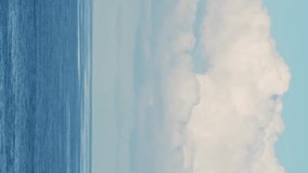 View of a calm ocean with clouds above it. Vertical video for social media.