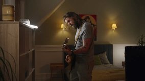 Man plays electric guitar in bedroom. Camera changes view to young girl living next door, recording dance for social networks on phone. Two rooms or apartments separated by wall. Neighborhood concept.