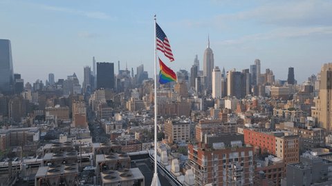 flying counter clockwise around pride and American flags on Manhattan roof Video Stok
