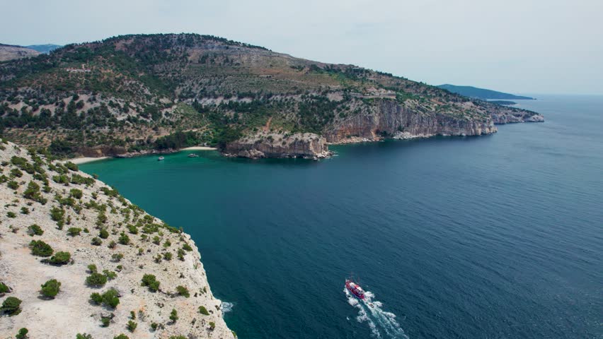 Aerial View Over A Seaside Cliff With Turquoise Water And Small Beaches With The Monastery of the Archangel Michael In The Background, Red Boat, Thassos, Greece Royalty-Free Stock Footage #1104935621