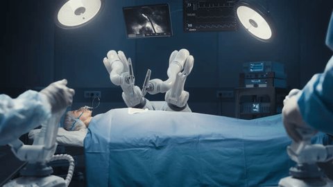 Two Surgeons Wearing Augmented Reality Headsets And Using High-Precision Remote Controlled Robot Arms To Operate On Patient In Futuristic Hospital. Doctors Working With Robotic Limbs, Observing Vitals Stock Video