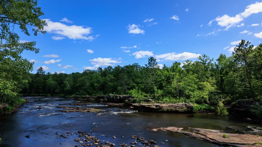 Time lapse of the clouds moving above Kettle River surrounded by forest in Minnesota.