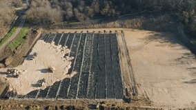An aerial video of tractor drivers working in a pit for the construction of a new building