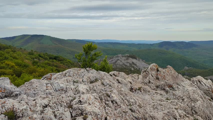 Panoramic view of the valley on top of the rocky ridge among the stones overlooking the beautiful valley. Outdoor and mountain hike background. Natural landscape in Bulgaria, Sliven