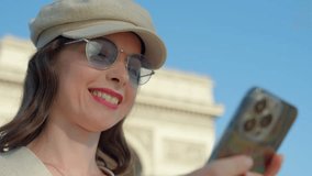 Smiling woman with smartphone on Arc de Triomphe background