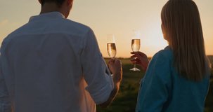 Couple with glasses of red wine watching the sunset over a picturesque valley. 4k video