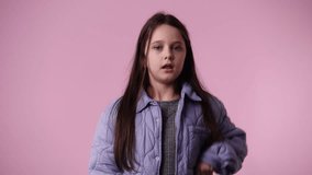 4k video of one child which stops and responds negatively to something over pink background.
