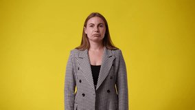4k video of one woman who doubts and waving his hands around over yellow background.
