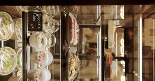 Glass counter with a variety of colorful pastries and desserts. Vertical video. In the coffee and pastry bar. Cakes and sweets in the window of a confectionery restaurant.